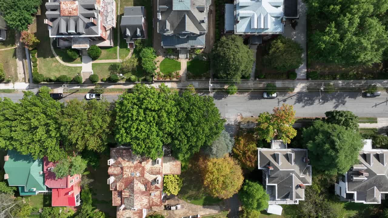 Aerial top down of an American residential neighborhood with tree-lined streets, detached houses, pitched and hip roofs, colorful facades and lush gardens in traditional suburban setting. VA, USA
