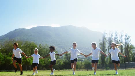 school kids holding hands and running in park