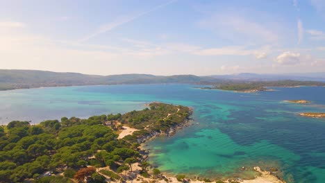 Backwards-moving-aerial-drone-clip-over-an-exotic-beach-in-Vourvourou,-Chalkidiki,-Greece
