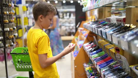boy preparing to school. young boy choosing school stationery in supermarket