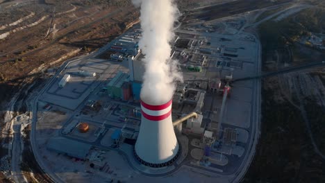 Drone-over-steam-chimney-new-coal-fired-power-station-plant-tilt-down-sunset