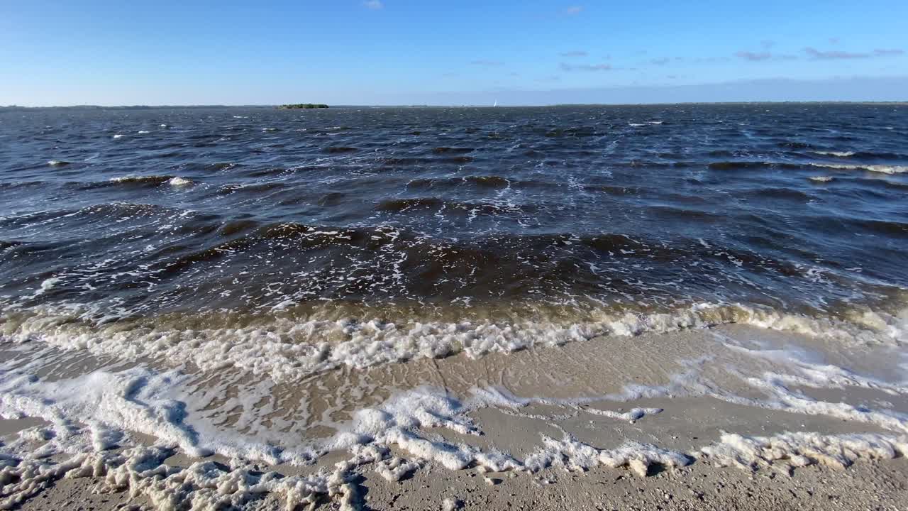 해변을 따라 파도가 천천히 모래 위로 굴러
