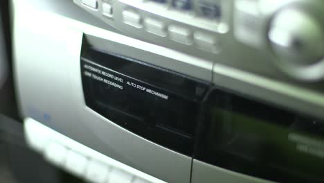 close-up of audio cassette being inserted into a retro style boombox