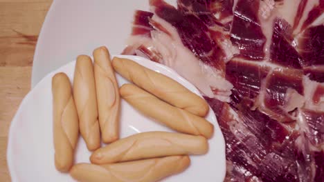 Spanischer-Jamon-Iberico-Mit-Picos-Auf-Sich-Drehenden-Platten,-Nahaufnahme-Von-Oben-Nach-Unten