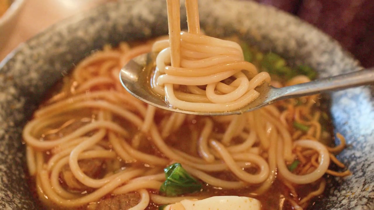 Cận cảnh đũa gắp bún từ tô súp bò cay ở Bangkok