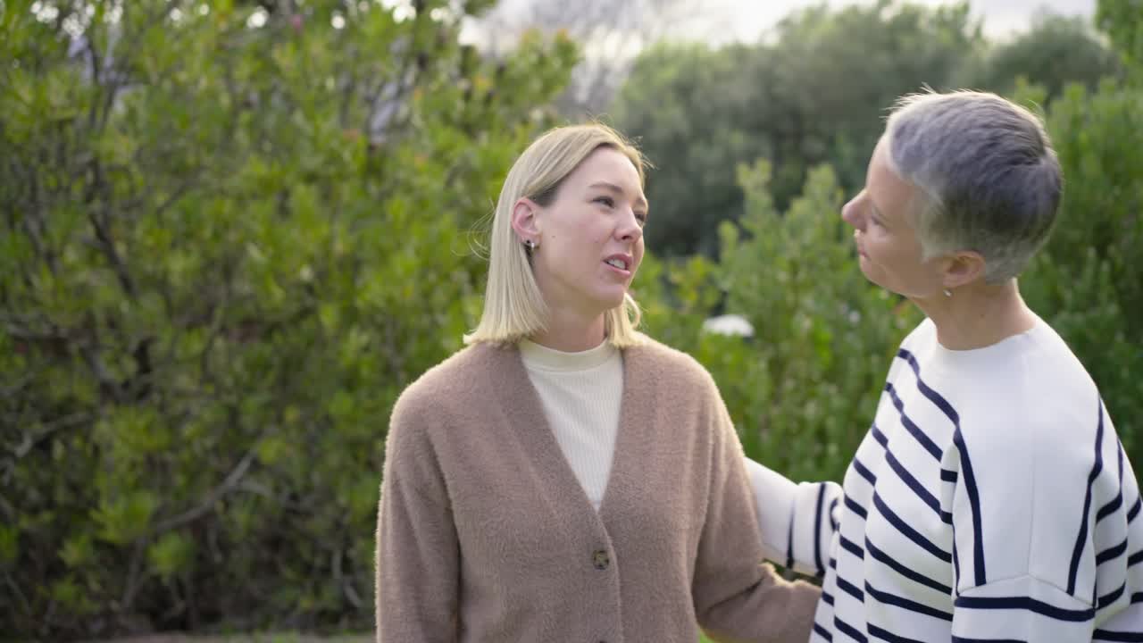 Madre e figlia chiacchierano per riallacciare i rapporti, si abbracciano e sorridono calorosamente in giardino