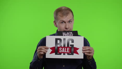 man shopper holding black friday deals advertisement in his month and showing big sale inscription