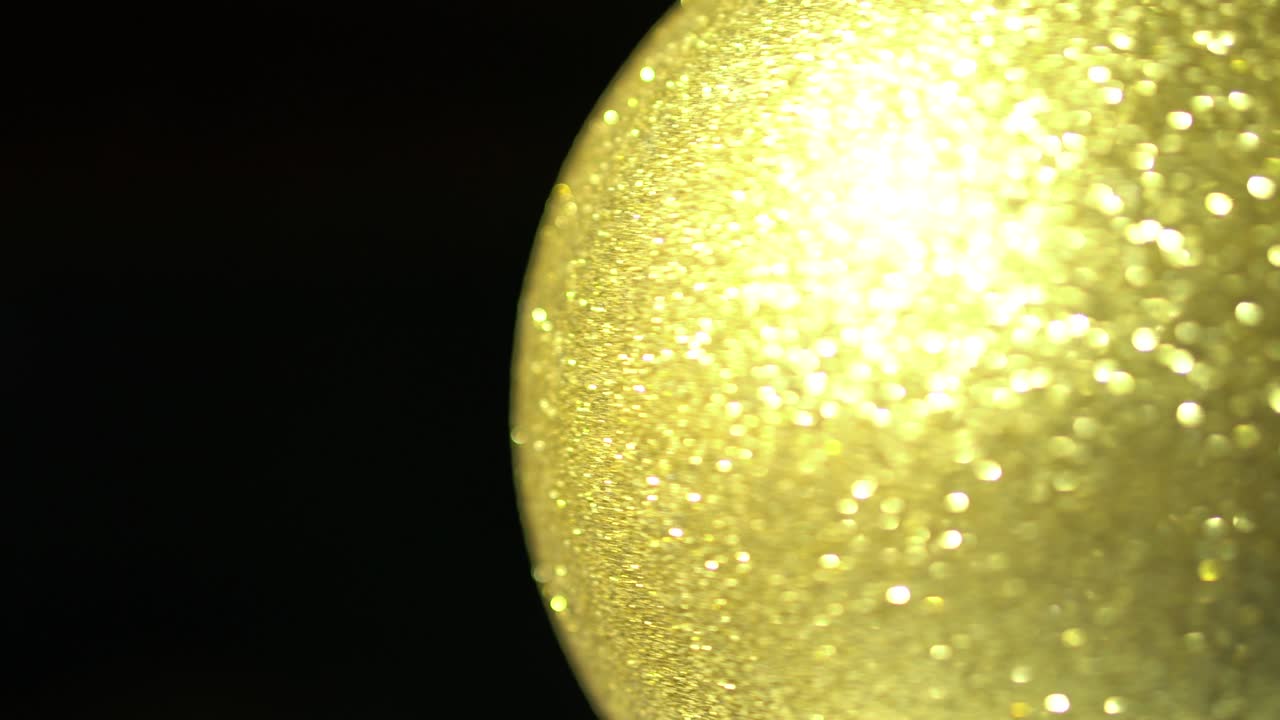 황금 크리스마스 공 장식은 검은색 배경에 고립되어 있으며 복사 공간으로 회전합니다. 장식, 박이는, 걱거리는, 클로즈업, 흐릿하고 부드러운 초점