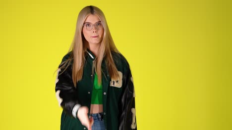 young blonde woman threatening and pointing by hand gun gesture, colorful studio shot