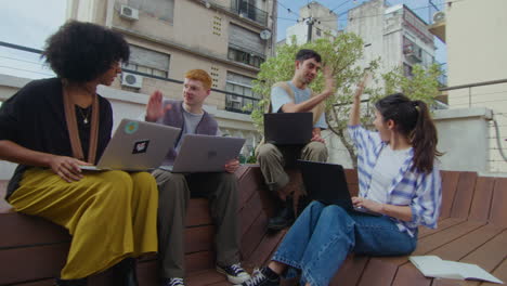 successful gen z business team high fiving at outdoor coworking space