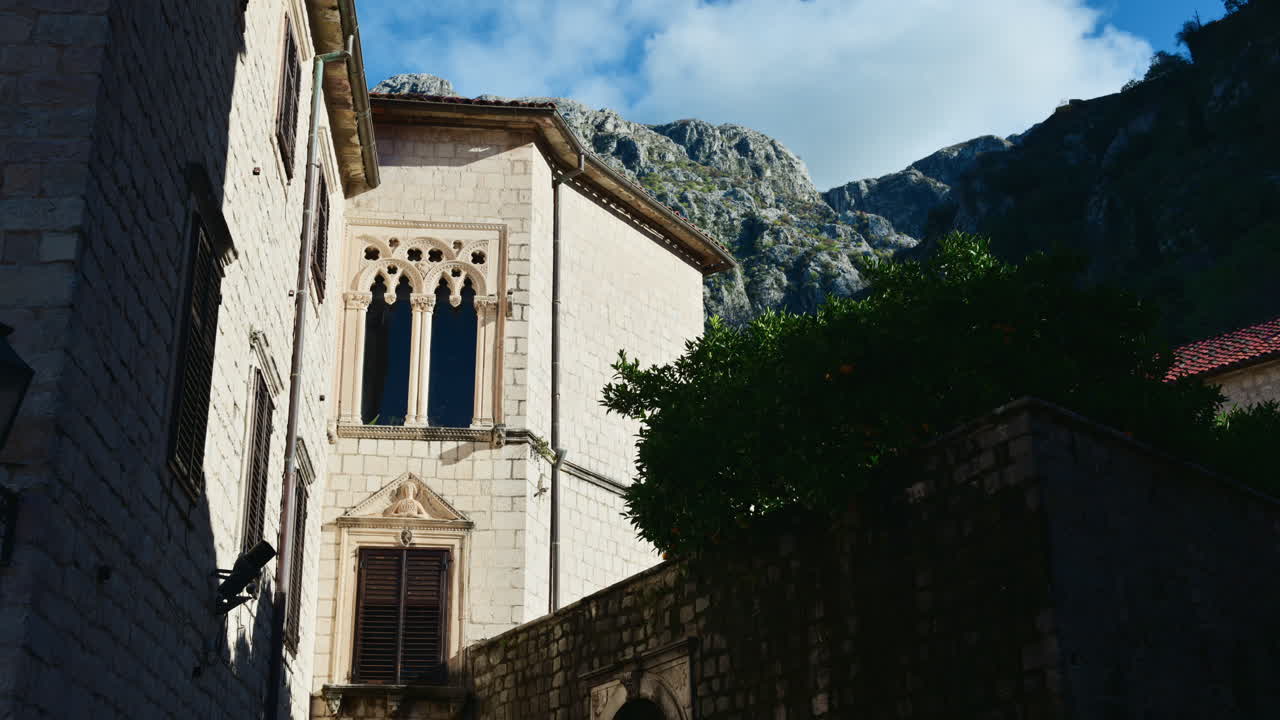 Edifici storici in pietra nel centro storico di Cattaro, Montenegro, con aspre montagne che si ergono alle spalle.