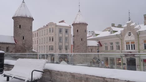 puerta viru de tallin en el casco antiguo durante una nevada en invierno con un banco en primer plano