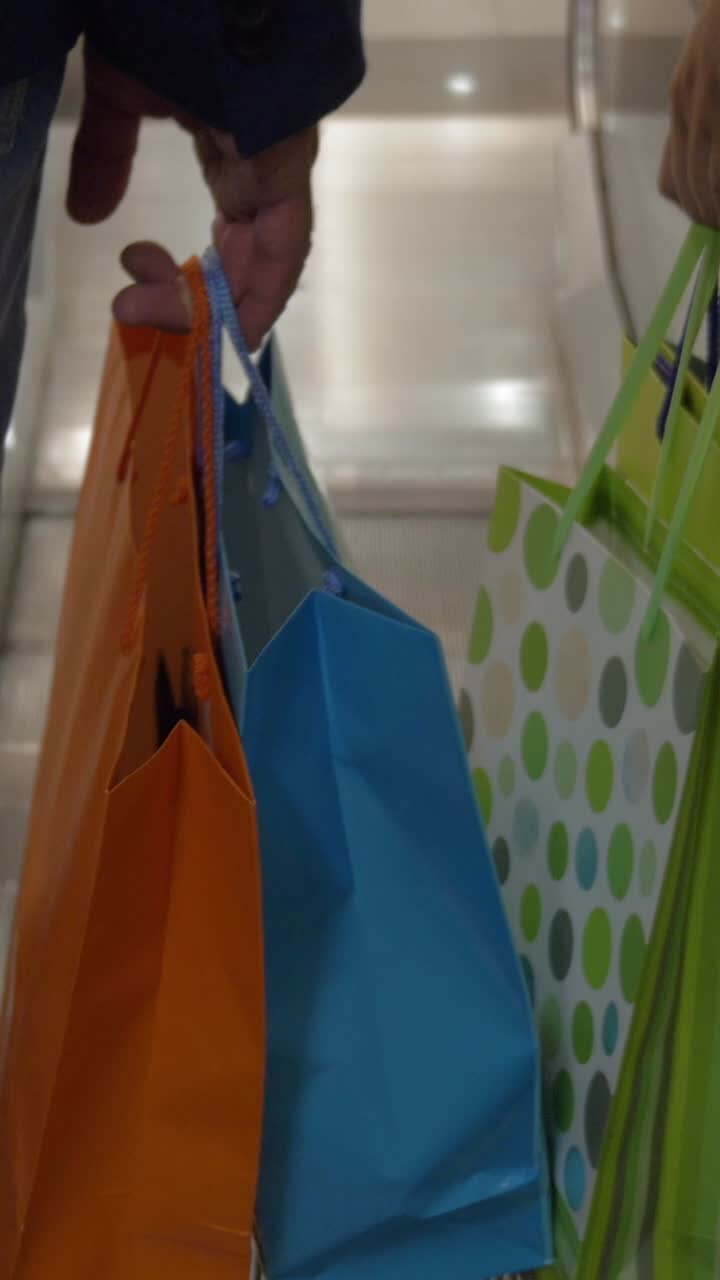 Persone con borse della spesa colorate sulla scala mobile e che camminano nel centro commerciale