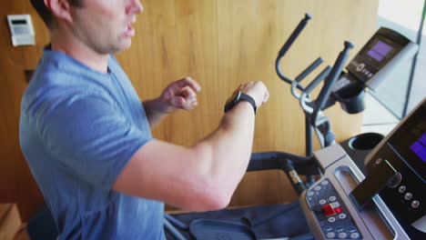 man exercising on treadmill at home checking smart watch