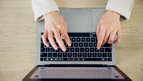 vista superior, las manos escribiendo en el teclado del portátil