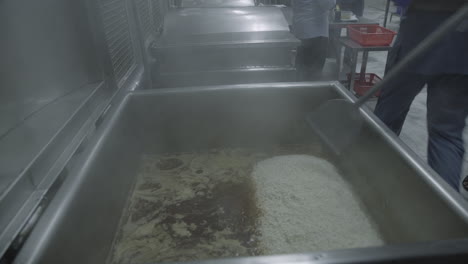 ready meal production line in a factory, a close up view of a man shifting rice into a machine and shaking it