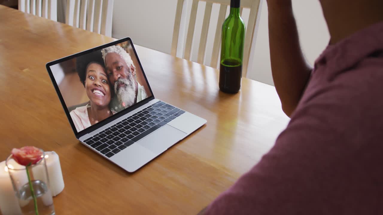 Mid section of african american man drinking wine while having a video call on laptop at home