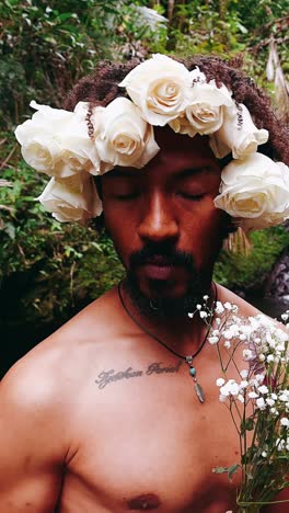 man adorned with white roses in a forest setting