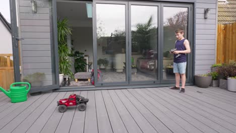 young boy at home outdoors in the garden playing with his rc car, truck, 4 x 4