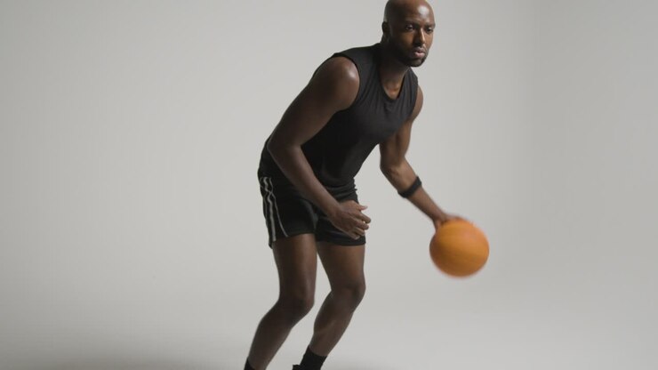 Studio-Action-Aufnahme eines männlichen Basketballspielers, der den Ball vor weißem Hintergrund dribbelt 1