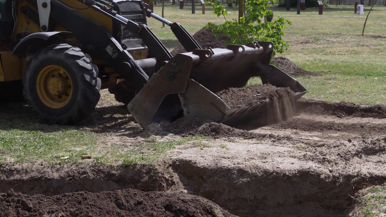 Bulldozer digging a trench to create a water retention system for plants in dry soil