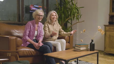 two little girls running and hugging their happy grandmothers who sitting on sofa in the living room at home 1