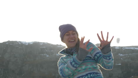 a woman in a snowball fight during sunset on top of a mountain in norway, slow motion