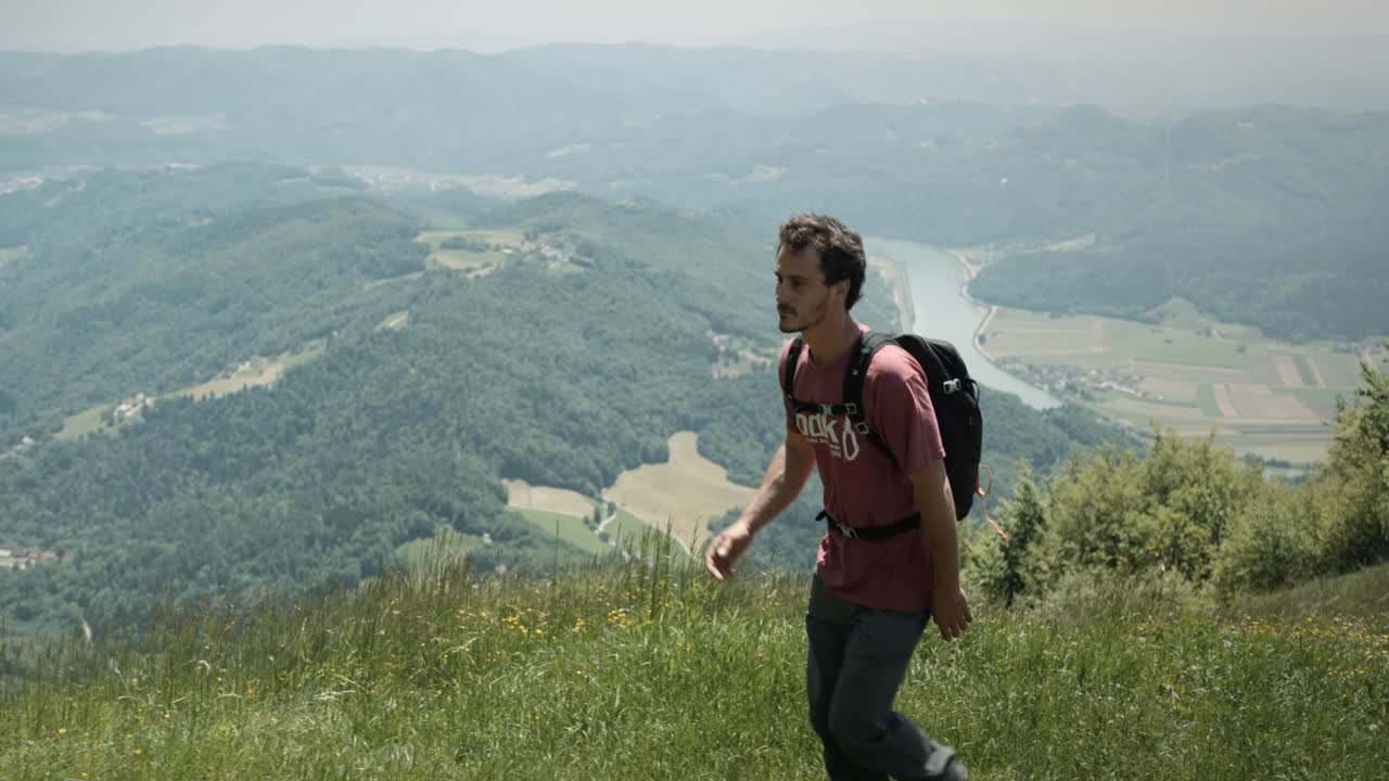 un joven excursionista que pasa frente a la cámara desde la dirección correcta hacia la izquierda