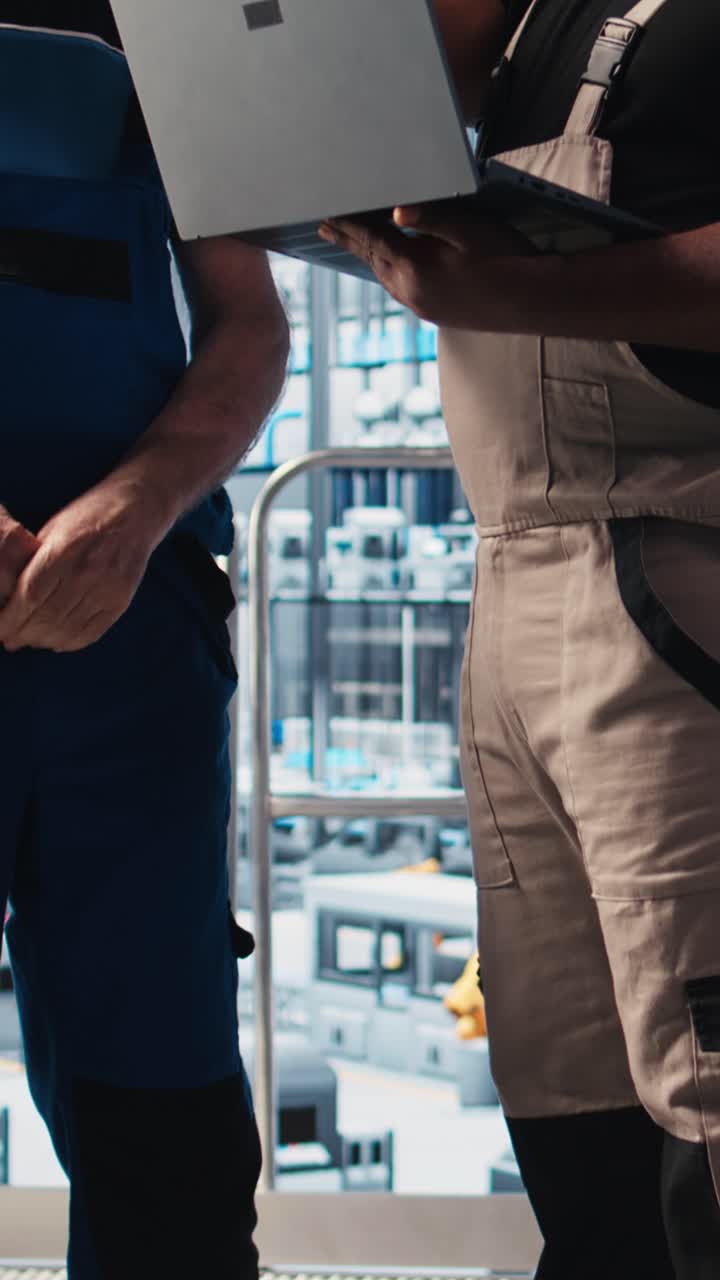 Video verticale. Ingegnere senior di una smart factory che insegna a un nuovo tirocinante a gestire i bracci robotici.
