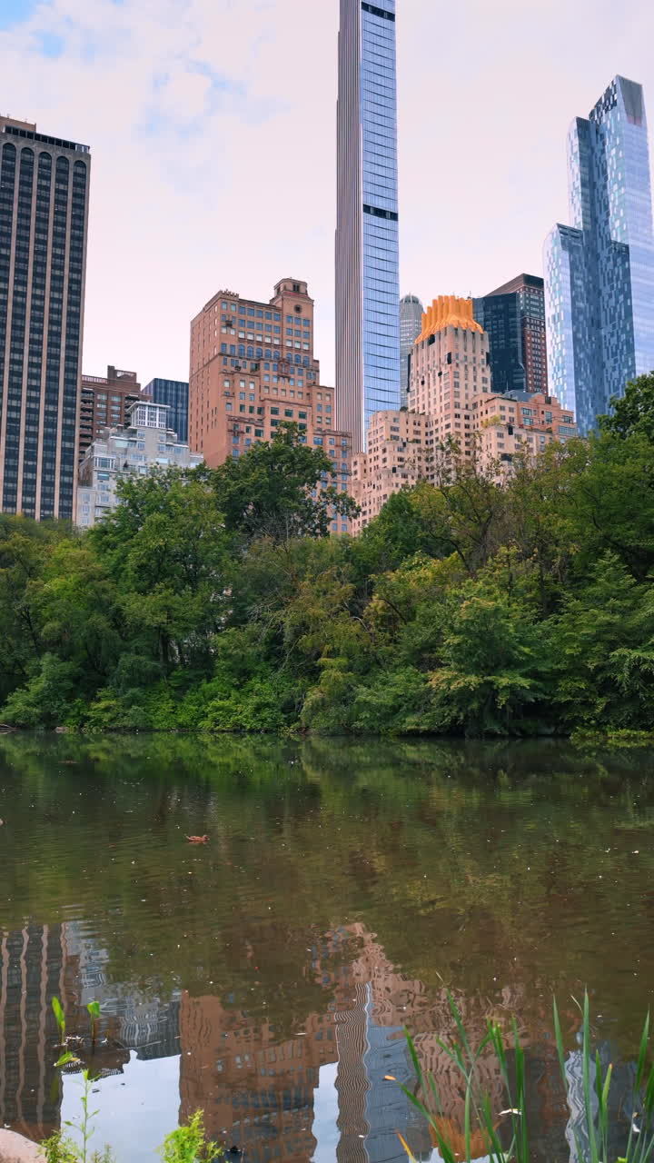 New York, USA, 8 luglio 2025: Relax in un parco vicino ai grattacieli. I visitatori si godono le acque calme di Central Park, circondati dagli imponenti edifici di New York in una giornata di sole