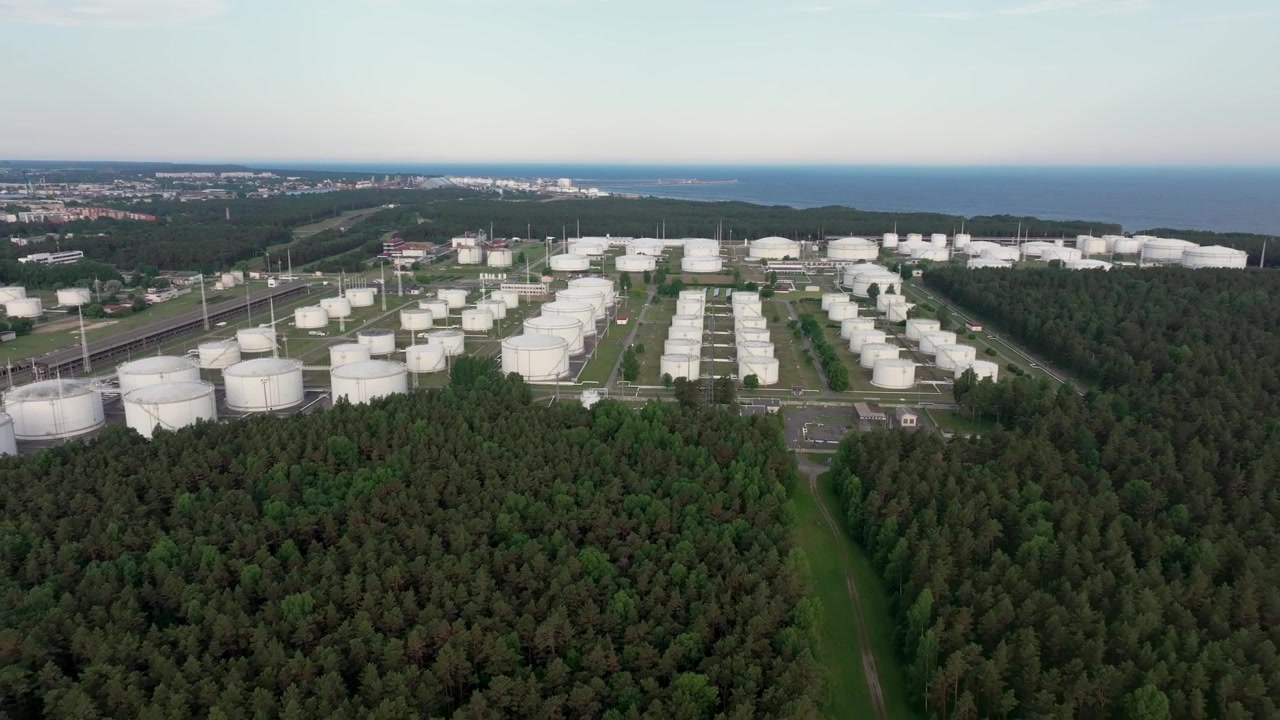 Ujęcia z drona dużego terminalu magazynowania ropy naftowej z białymi zbiornikami, infrastrukturą kolejową i Portem Ventspils na Morzu Bałtyckim na Łotwie
