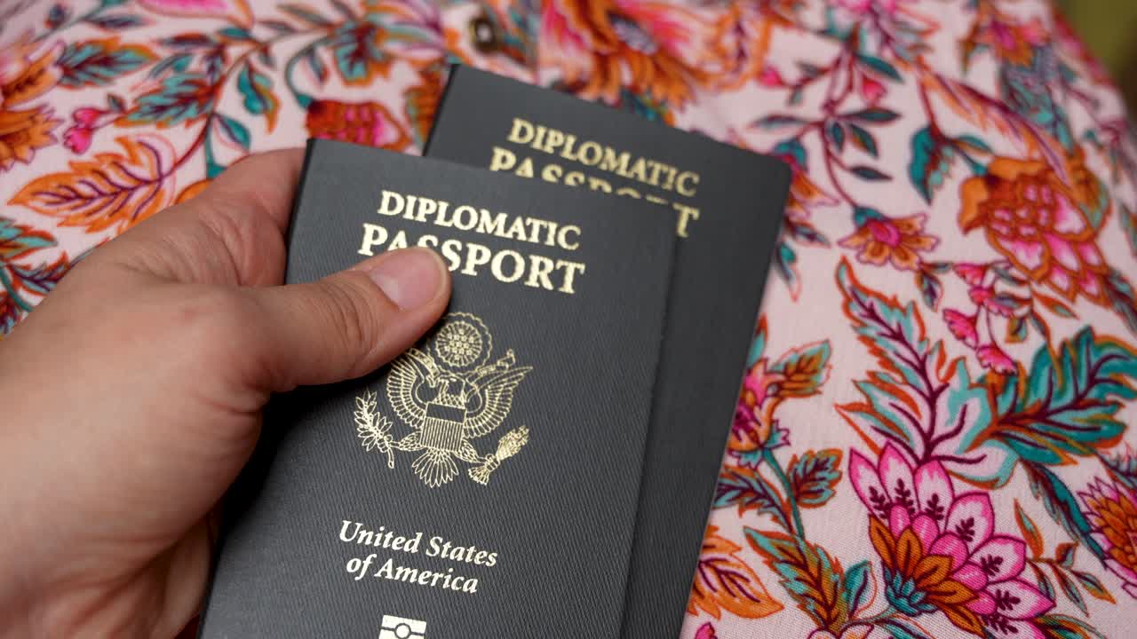 Two black United States diplomatic passports in the hand of a woman, close up