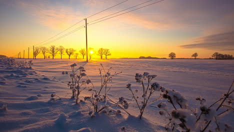 Time-lapse-of-golden-sunset-hiding-at-horizon-during-snowy-winter-day-between-countryside-fields-and-flying-clouds-at-sky