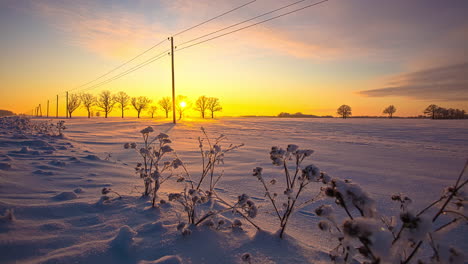 lapso de tiempo de puesta de sol dorada escondida en el horizonte durante un día nevado de invierno entre campos rurales y nubes voladoras en el cielo