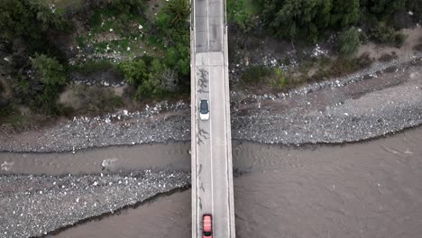 Drop-down-view-of-fly-over-bridge-and-river-with-cars-in-Santiago,-Chile