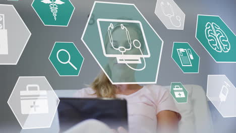 animation of medical icons over caucasian woman using tablet on bed in hospital