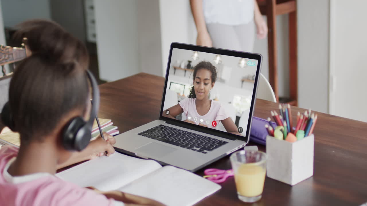 composición de una colegiala afroamericana en una computadora portátil aprendiendo en línea con una colegiala biracial