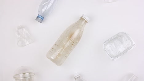 different used dirty plastic disposable tableware and garbage, bottles cups and containers moves on white background, seamless looping, stopmotion animation, big ecological pollution problem