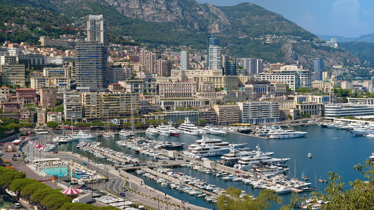 Aerial view of white boats docked in the Monaco Marina with the skyline on the background