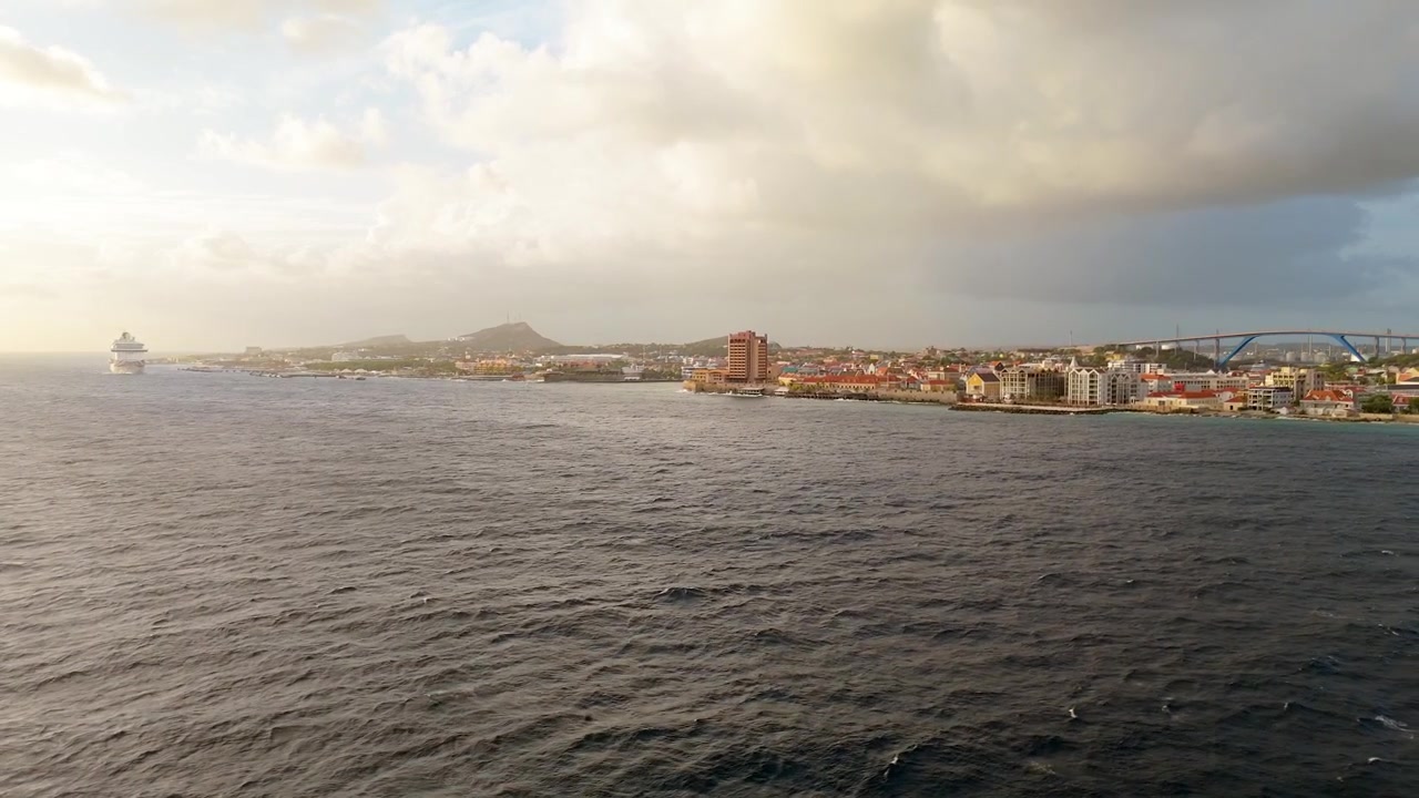 Ampia ripresa aerea con drone al tramonto al largo del porto di Curaçao con una nave da crociera a sinistra e il ponte Queen Juliana visibile in lontananza