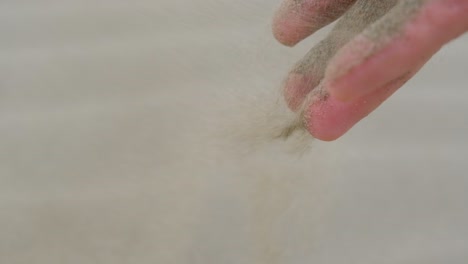 남자가 바람에 모래를 뿌리면서 손을 슬로우 모션으로 클로즈업