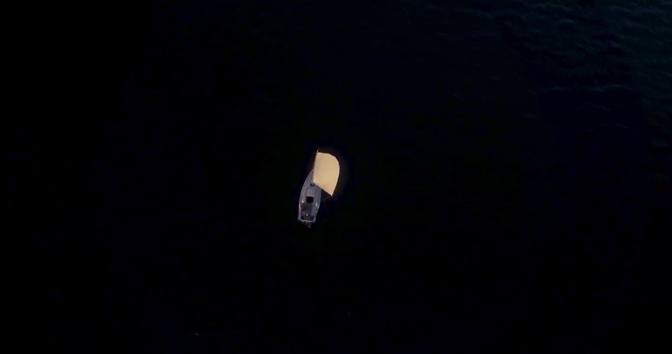 Barca a vela sul lago tra le montagne al tramonto