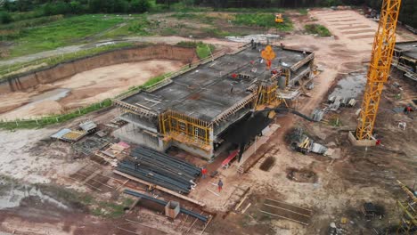 orbiting aerial scene in dynamic motion, moving away from a group of buildings under construction with their workers and the central crane