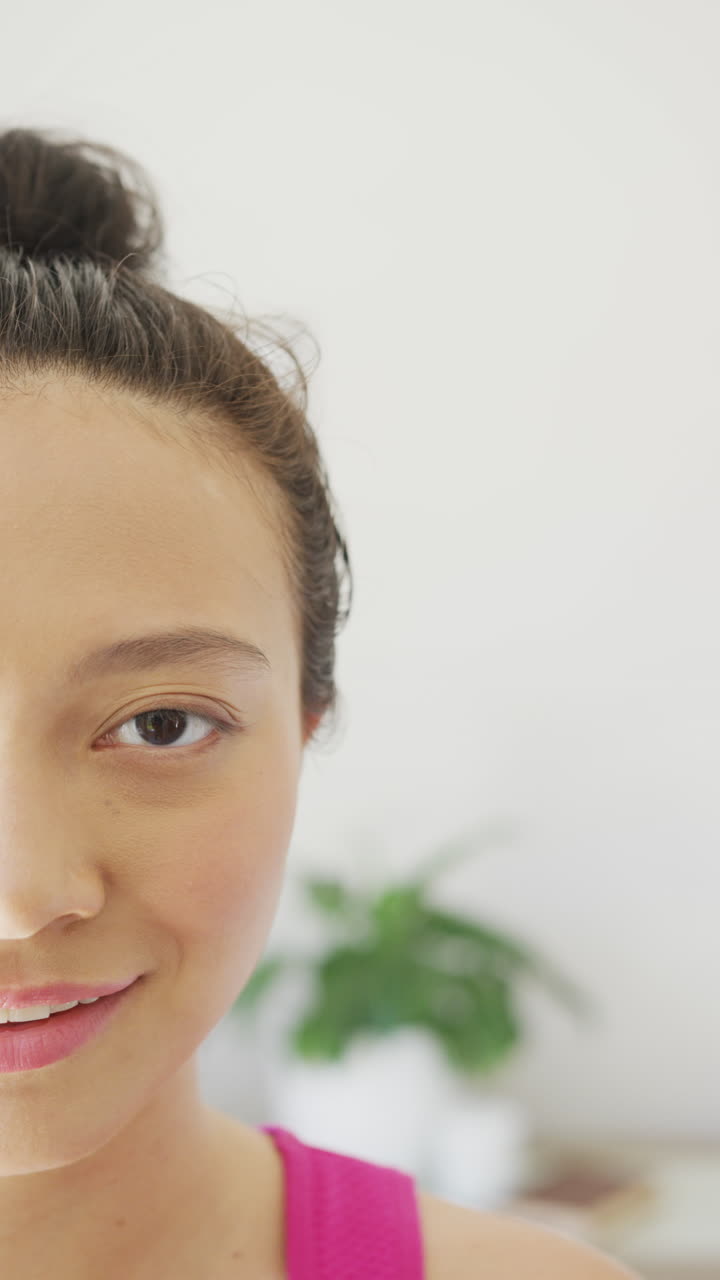 Vertical video of portrait of happy asian woman smiling in bedroom, in slow motion