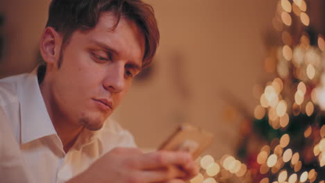 happy man using cellphone at illuminated home during christmas