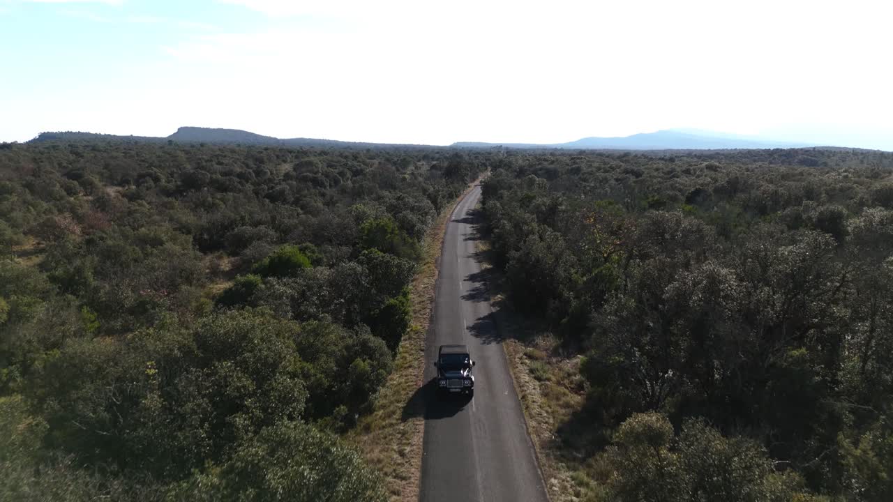 una vista aérea revela una carretera rural con un vehículo en un viaje por carretera