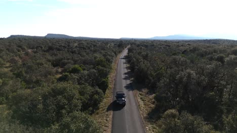 Aerial-view-reveals-countryside-road-with-vehicle-on-road-trip-journey