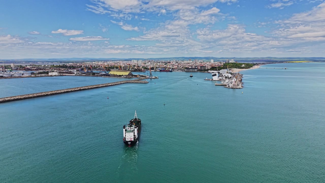 Una grande nave entra in un porto trafficato in una giornata serena con cielo azzurro