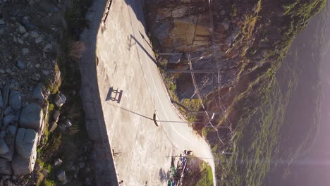 winding rocky mountain road on sunny day in vietnam, aerial vertical video