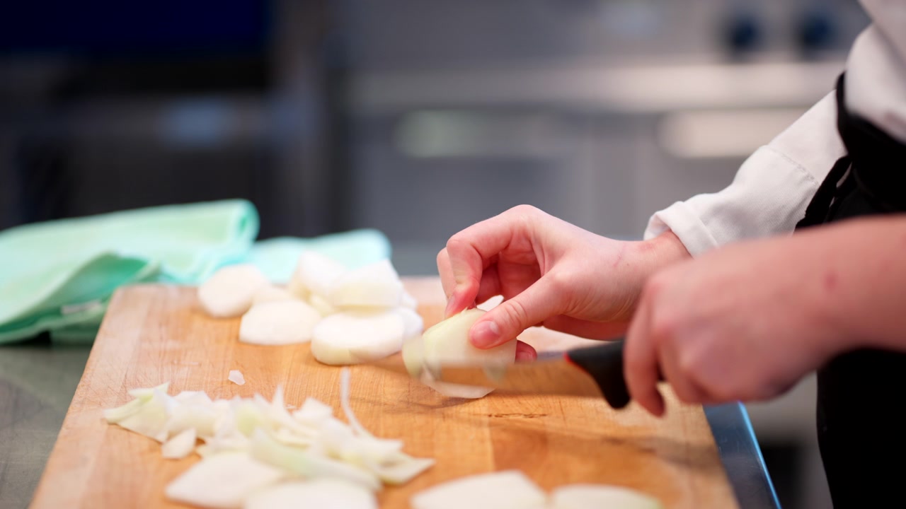 Peeling potatoes on a cutting board with a paring knige in a professional kitchen workspace during food prep